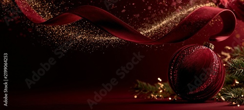 Luxury Crimson Velvet Christmas Ornament with Flowing Ribbon and Golden Sparkles on Burgundy Background with Copy Space