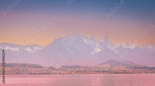 Картината върху платно Scenic Panorama with Sunset Over Snow-Capped Mountain Range and Rural Landscape