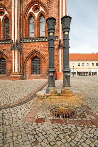 Pair of historic 19th-century cast iron street water pumps beside the old town hall, photographed in portrait format.