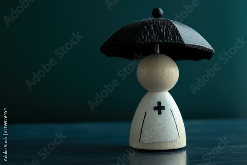 Wooden medical figure under umbrella showing healthcare coverage