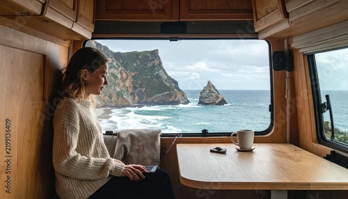 Woman relaxing in camper van overlooking ocean.