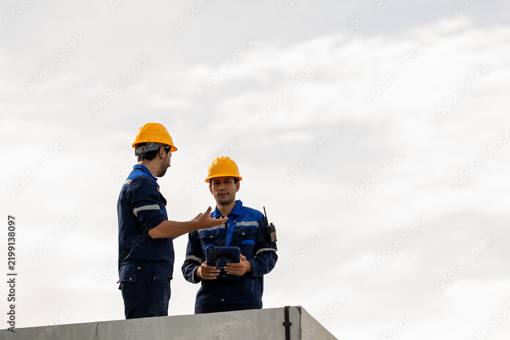 Fototapeta premium Engineer industrial worker in safety helmet discussing construction plan on concrete structure under cloudy sky