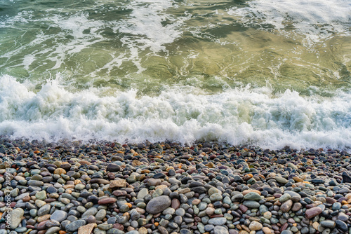 Ocean waves crashing on a smooth stone pebble beach in Lima, Peru.