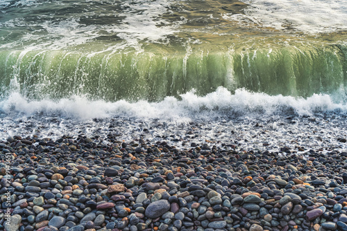 Ocean waves crashing on a smooth stone pebble beach in Lima, Peru.