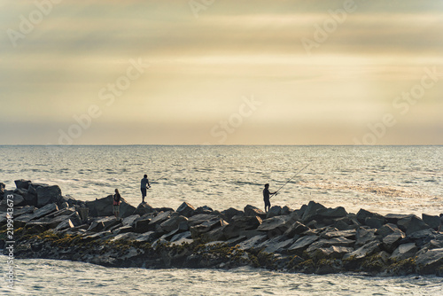 Lima, Peru - March 30, 2025: Two local man fishing from the rocks of Espigon Waikiki, in Lima