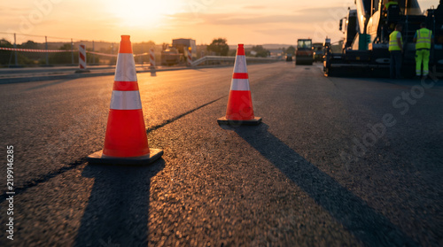 Orange traffic cones marking road construction zone during golden sunset
