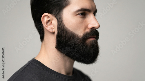 Man with well groomed thick black beard profile view