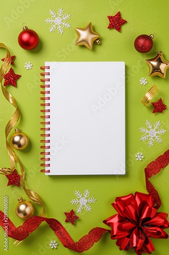 Decorative Festive Setup With Blank Notebook and Holiday Ornaments on Green B...