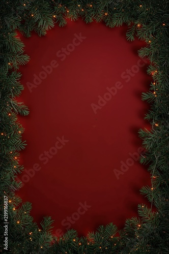Christmas Decoration Background With Green Branches and Lights on Red Surface