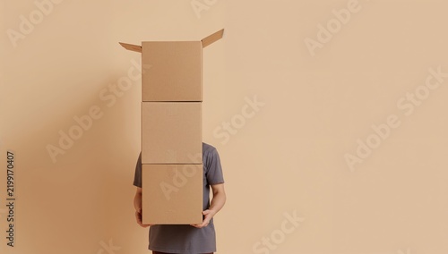 Person Holding Cardboard Boxes in Front of Their Face Against a Simple Beige ...