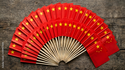 Small toothpick Chinese flags arranged in semicircular fan shape on wood background.