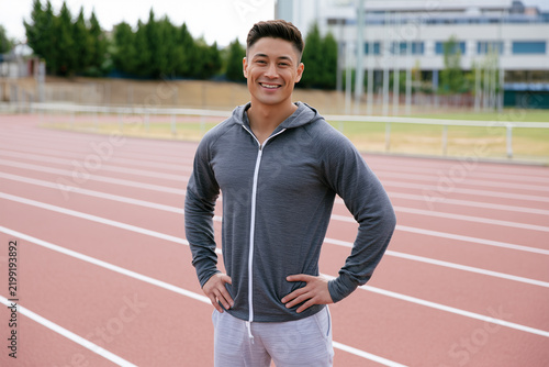 Athlete stands confidently on a track field at a sports facility
