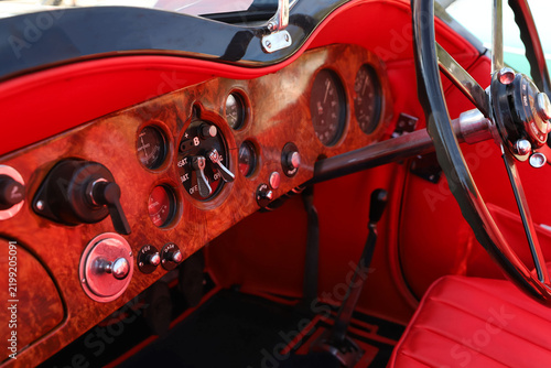 Vintage classic car interior with wooden dashboard and red leather seats