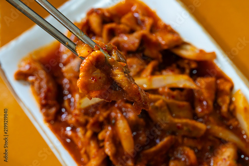 Chopsticks Holding a Tender Piece of Spicy Korean Stir-Fried Pork