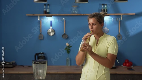 sporty young woman drinking fruit handmade smoothie in the kitchen at home. Copy space