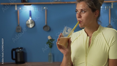 sporty young woman drinking fruit handmade smoothie in the kitchen at home. copy space