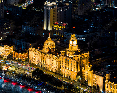 Photography Night view of the historic buildings illuminated along the Bund, glowing with golden lights above busy street traffic