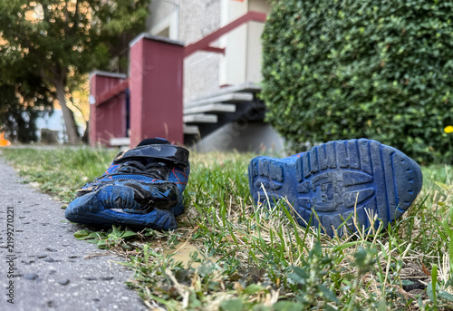 Obraz na plátně Conceptual image of a discarded children's shoe on the street, illustrating poverty, child neglect and social issues