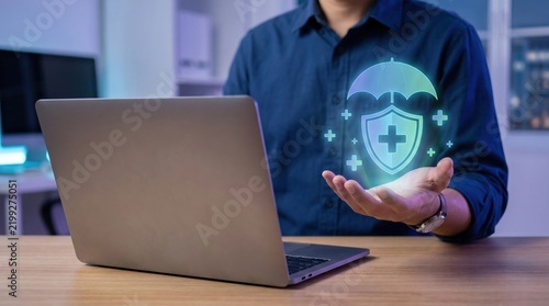 Digital healthcare and insurance concept showing a professional using a laptop while holding a glowing medical shield icon, symbolizing online protection, health security, coverage, and trusted care.