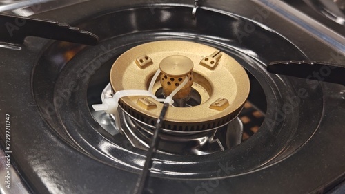Konstfotografi Close-up detail of a gas stove brass burner secured with a white cable tie