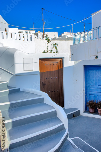 A curved whitewashed stairway leads through a traditional residential passage in Megalochori, Santorini, Greece.
