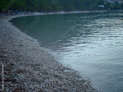 Serene coastal village scene featuring a peaceful pebble beach and calm sea symbolizing tranquility.