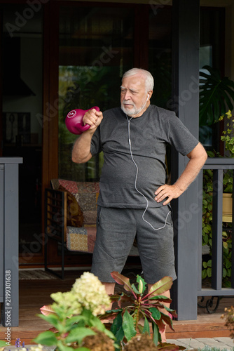 Elderly man exercises with a kettlebell at home in the morning