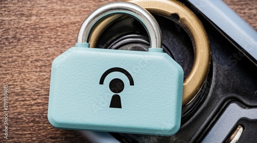 Close-Up of a Small Teal Padlock with Keyhole Symbol Beside a Smartphone on a Wooden Desk