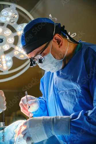 Focused surgeon wearing magnifying loupes during surgery in an operating room