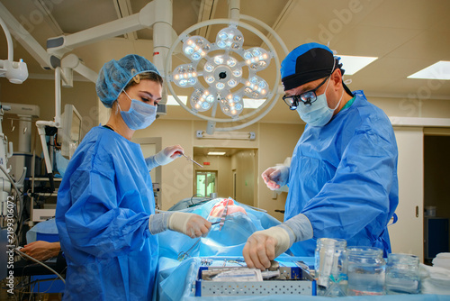 Surgeon and assistant performing surgery under operating room lights