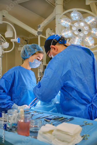 Surgeon and assistant performing surgery under operating room lights