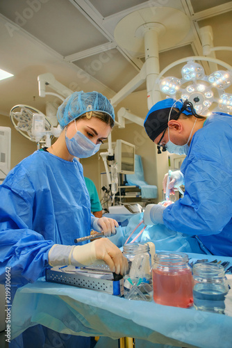 Surgeon and assistant performing surgery under operating room lights
