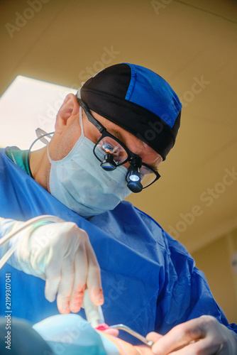 Focused surgeon wearing magnifying loupes during surgery in an operating room