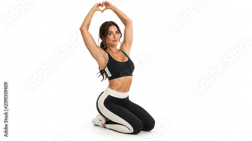 Fit woman in black sportswear making heart gesture with hands