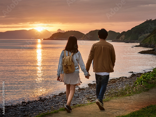 カップルが夕日を眺めて海岸を散歩