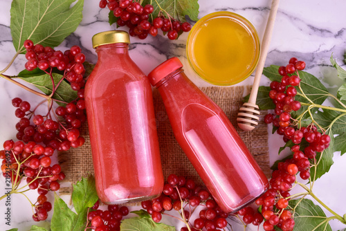 Vitamin-rich viburnum and honey drink in small bottles. Flat lay.
