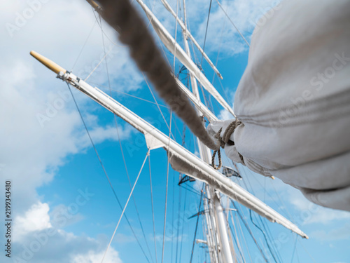 Canvastavla A tilted view into the rigging of a tall ship, yard and furled sail sweeping past the mast and a bright sky full of clouds
