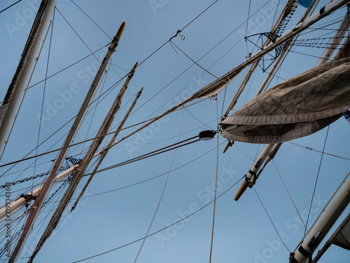Canvastavla A graphic tangle of masts, yards, ropes and half furled sails seen straight up against an even blue evening sky