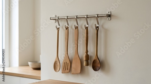A collection of wooden kitchen accessories hanging on a metal wall rack inside a modern home culinary space interior