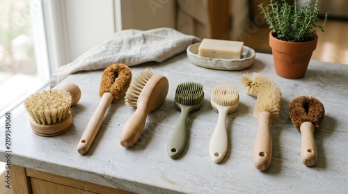 A collection of sustainable wooden kitchen accessories including various dish brushes and cleaning tools arranged on a white stone countertop