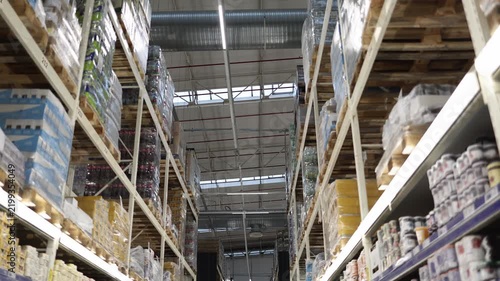 Wholesale supermarket aisle with tall industrial shelves loaded with bulk foods and drinks supplies on wooden pallets showing warehouse retail inventory and storage stock