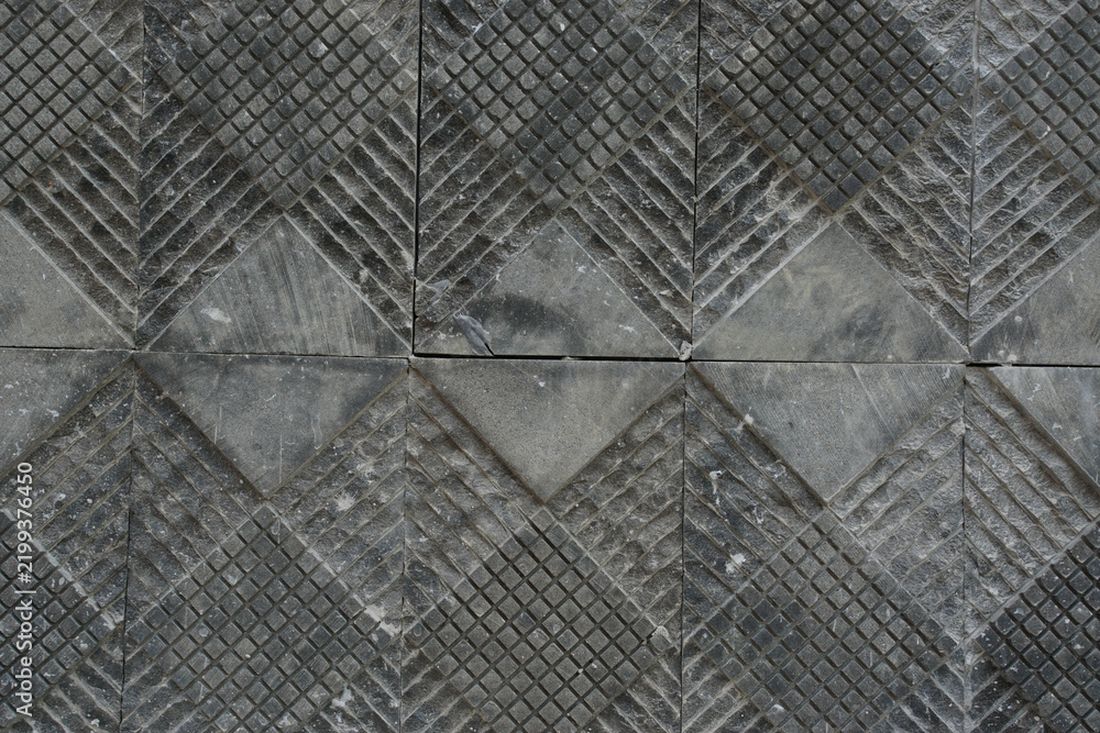 Obraz premium Dark gray natural stone wall cladding with a geometric checkered pattern and grooved surface, creating a modern architectural texture background