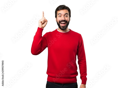 Excited man in a red sweater pointing his finger upward to show an idea