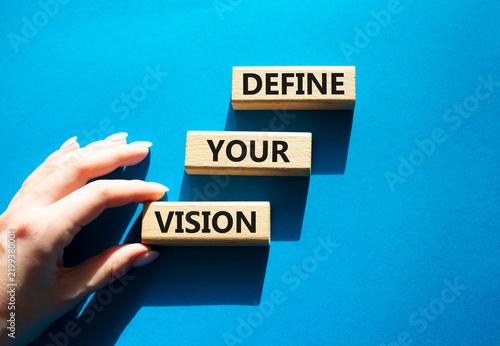 Concept words define your vision on wooden blocks arranged as steps. Businessman hand arranging wooden blocks. Strategic planning and goal setting concept. Blue background. Copy space.