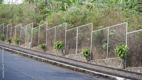 Принти на полотні Wire mesh security fence panels installed on a sloped concrete retaining wall beside an inclined street