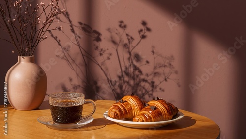 Coffee and Croissants on a Table With Flowers in a Vase and Shadows on the Wall