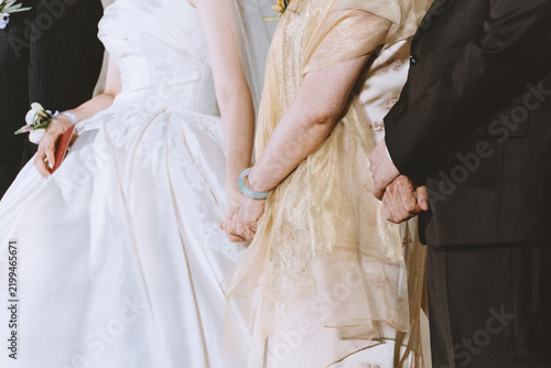 Foto Wedding ceremony in New York City: bride in white gown holding hands with mother