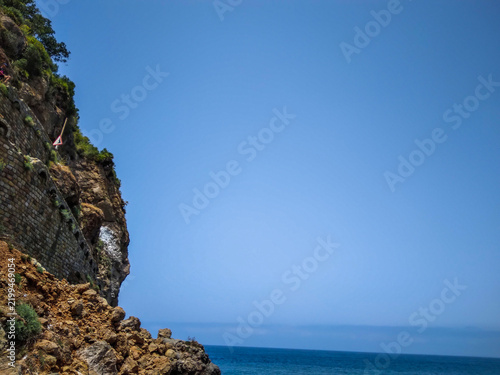 Quadro su tela Steep rocky cliff formation standing tall beside the vast deep blue ocean under