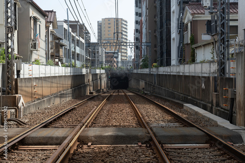 住宅街の間に切り拓かれた線路が地下のトンネルへと向かう、奥行きのある鉄道風景