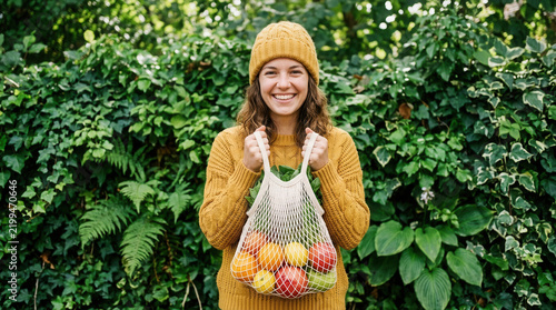 Young Woman With Bag Of Fresh Fruit In Lush Greenery
